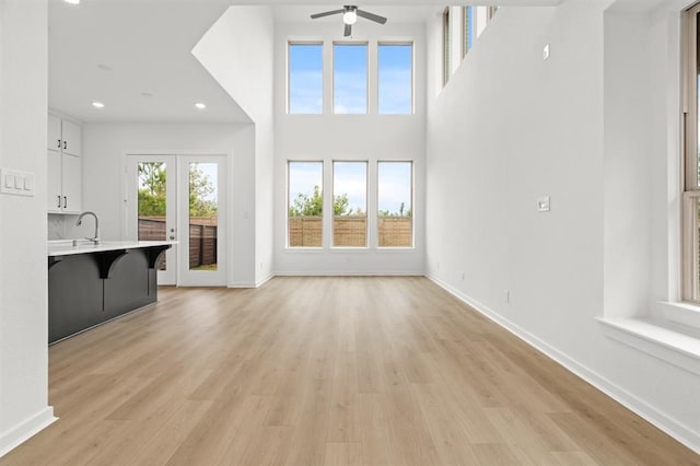 unfurnished living room featuring sink, ceiling fan, and light wood-type flooring