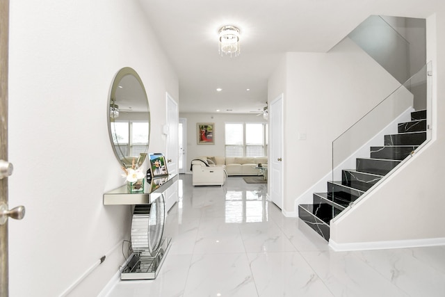 foyer entrance with marble finish floor, ceiling fan, stairway, and baseboards