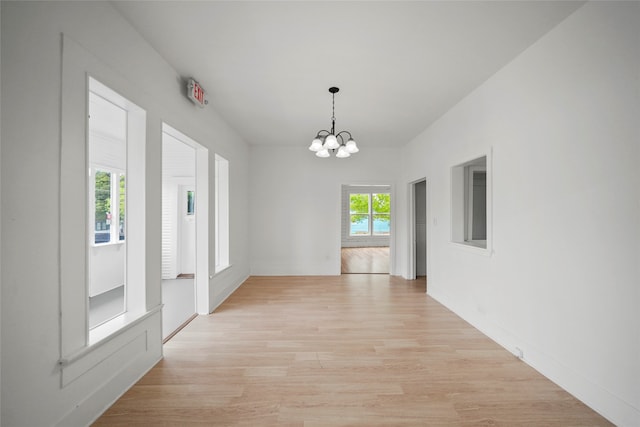 unfurnished dining area with an inviting chandelier and light hardwood / wood-style floors