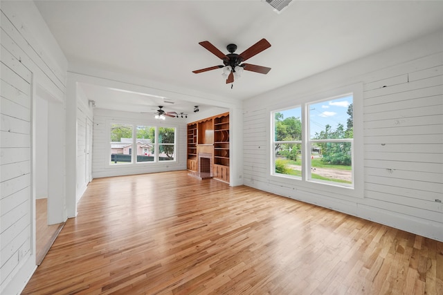 unfurnished living room with light wood-type flooring, ceiling fan, and plenty of natural light