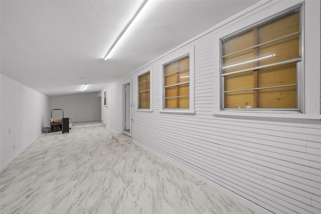 basement with built in features, wood walls, and a textured ceiling