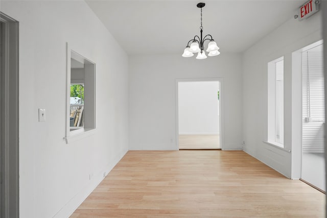 spare room with light hardwood / wood-style floors and a chandelier