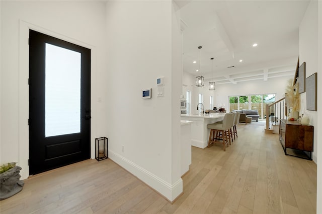 entrance foyer featuring sink, light hardwood / wood-style floors, and beam ceiling