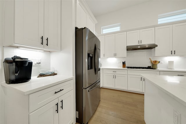 kitchen with white cabinets, stainless steel refrigerator with ice dispenser, light stone counters, and plenty of natural light