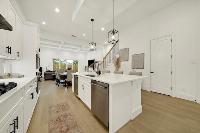 kitchen with white cabinets, appliances with stainless steel finishes, a center island with sink, and light hardwood / wood-style flooring