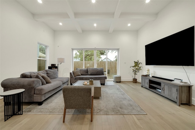 living room featuring light hardwood / wood-style floors, beamed ceiling, and a high ceiling