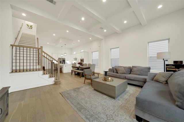 living room featuring light hardwood / wood-style floors, beamed ceiling, and coffered ceiling