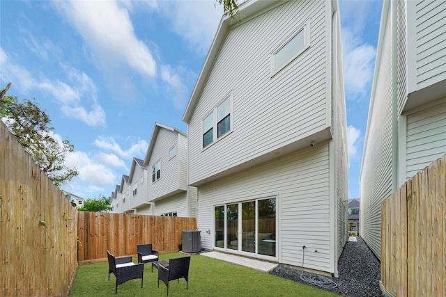 rear view of property featuring central air condition unit and a lawn