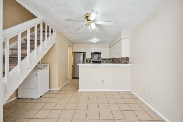 kitchen featuring washer / dryer, white cabinets, tasteful backsplash, ceiling fan, and stainless steel refrigerator