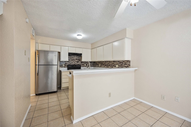 kitchen with kitchen peninsula, decorative backsplash, white cabinetry, ceiling fan, and stainless steel refrigerator