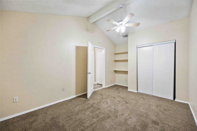 unfurnished bedroom with ceiling fan, a textured ceiling, carpet flooring, a closet, and lofted ceiling with beams