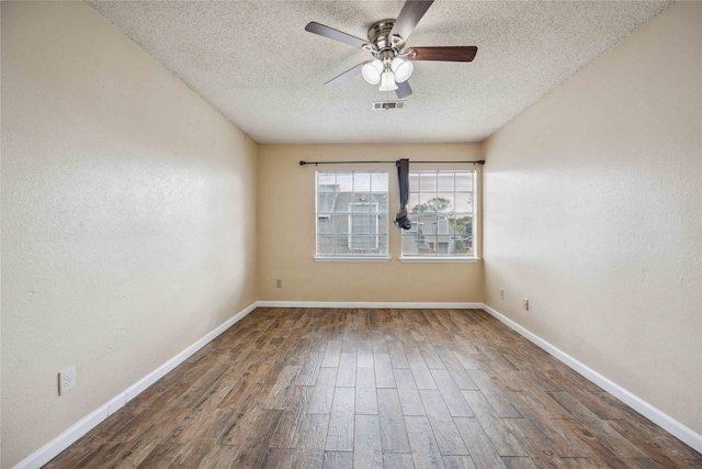 spare room featuring dark wood-type flooring, a textured ceiling, and ceiling fan