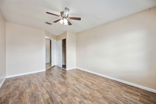 unfurnished room with a textured ceiling, wood-type flooring, and ceiling fan