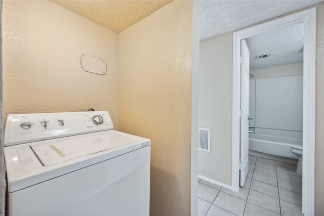 washroom with washer / dryer, a textured ceiling, and light tile patterned floors