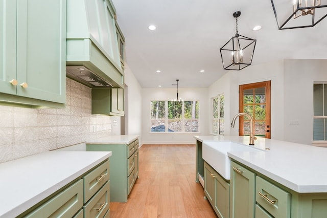 kitchen featuring sink, green cabinetry, an island with sink, and plenty of natural light