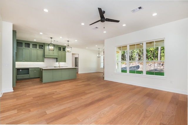 kitchen featuring light hardwood / wood-style floors, a kitchen island with sink, and green cabinets