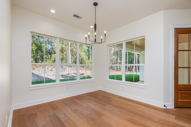 unfurnished dining area featuring a notable chandelier and hardwood / wood-style flooring