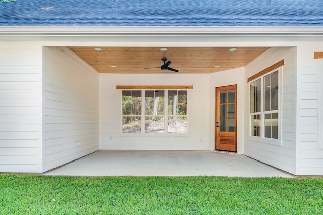 view of exterior entry featuring a patio, ceiling fan, and a lawn