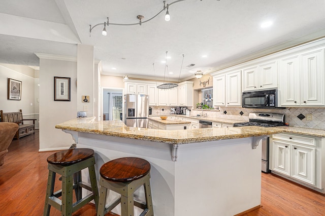 kitchen with backsplash, light hardwood / wood-style floors, white cabinetry, and stainless steel appliances