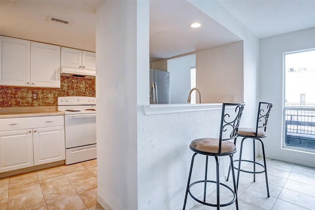 kitchen with white cabinets, a wealth of natural light, stainless steel fridge, and white stove