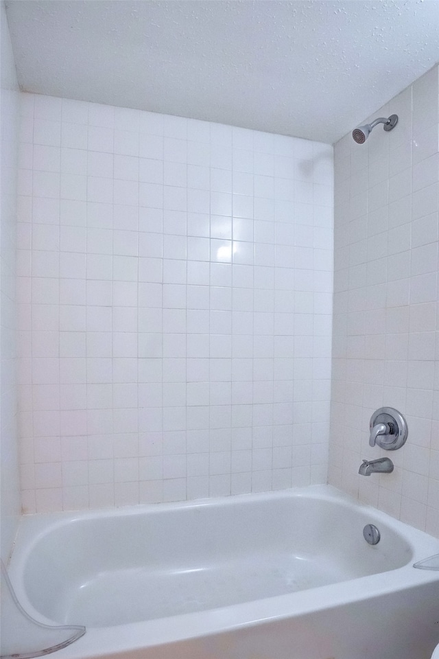 bathroom featuring tiled shower / bath and a textured ceiling