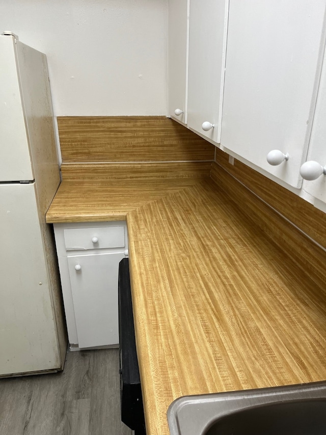 interior space featuring white cabinets, hardwood / wood-style floors, and white fridge