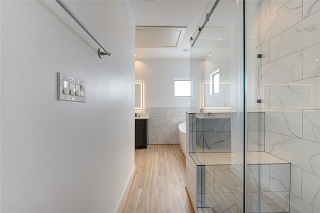 bathroom featuring vanity, wood-type flooring, a shower with shower door, and tile walls