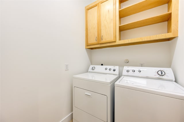 clothes washing area with washer and dryer and cabinets