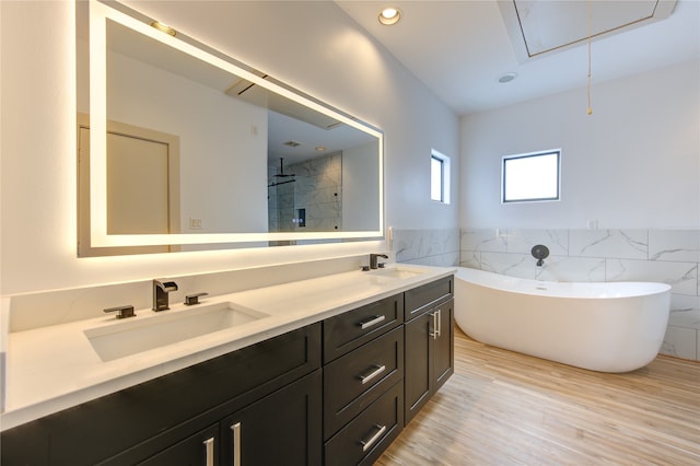 bathroom featuring vanity, tile walls, wood-type flooring, and plus walk in shower