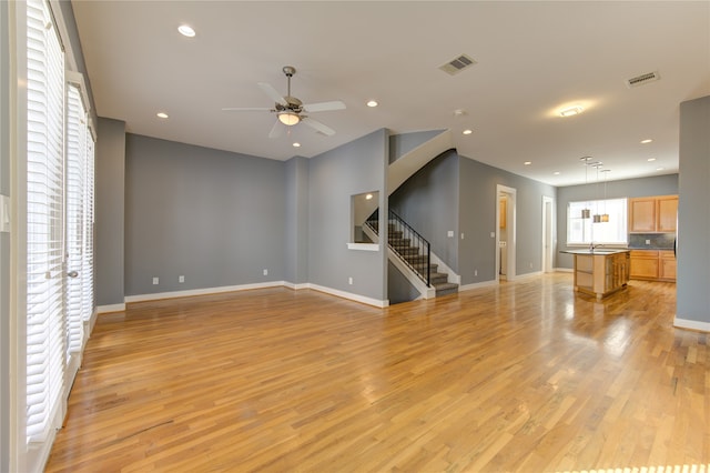 unfurnished living room with sink, light wood-type flooring, and ceiling fan