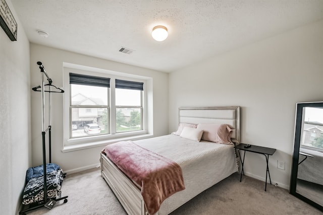 carpeted bedroom featuring multiple windows and a textured ceiling