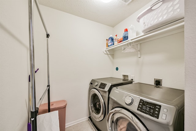 clothes washing area featuring washer and dryer and a textured ceiling