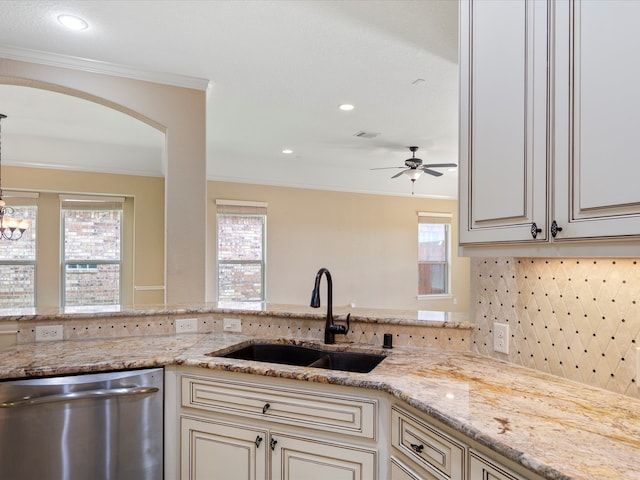 kitchen with sink, ornamental molding, light stone countertops, stainless steel dishwasher, and cream cabinetry