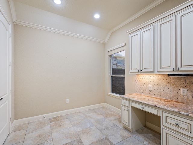 kitchen with light stone counters, vaulted ceiling, tasteful backsplash, ornamental molding, and built in desk