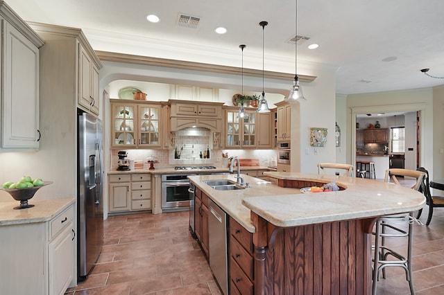 kitchen with a kitchen breakfast bar, an island with sink, sink, pendant lighting, and appliances with stainless steel finishes