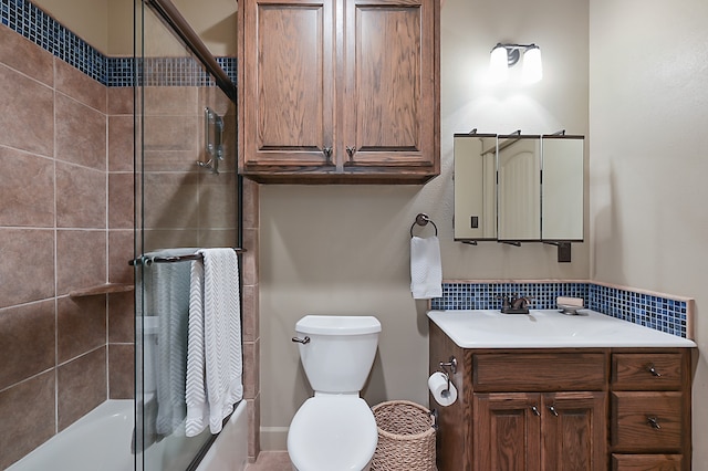 full bathroom featuring vanity, bath / shower combo with glass door, and toilet