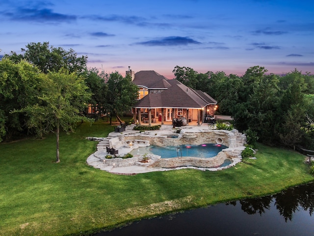 pool at dusk featuring a patio, a yard, and an in ground hot tub