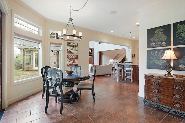 dining room featuring an inviting chandelier, crown molding, a healthy amount of sunlight, and dark tile patterned floors