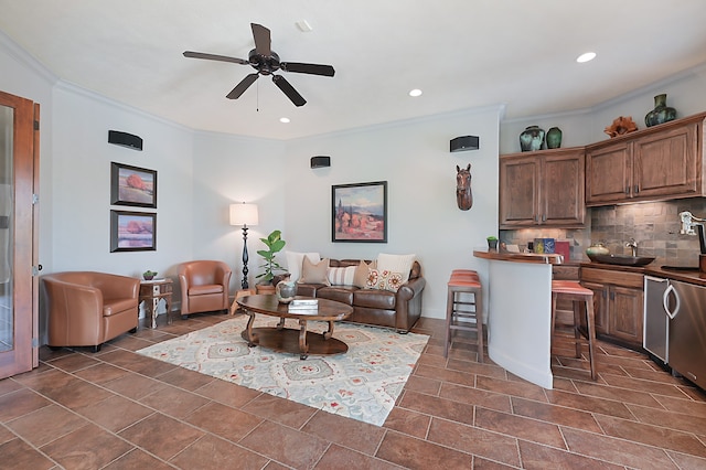 living room with ornamental molding, sink, dark tile patterned flooring, and ceiling fan