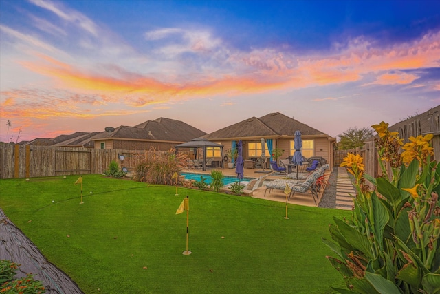 back house at dusk with a gazebo, a patio area, and a fenced in pool