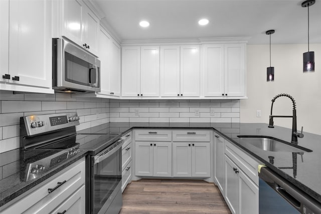 kitchen with stainless steel appliances, hanging light fixtures, hardwood / wood-style flooring, sink, and white cabinetry