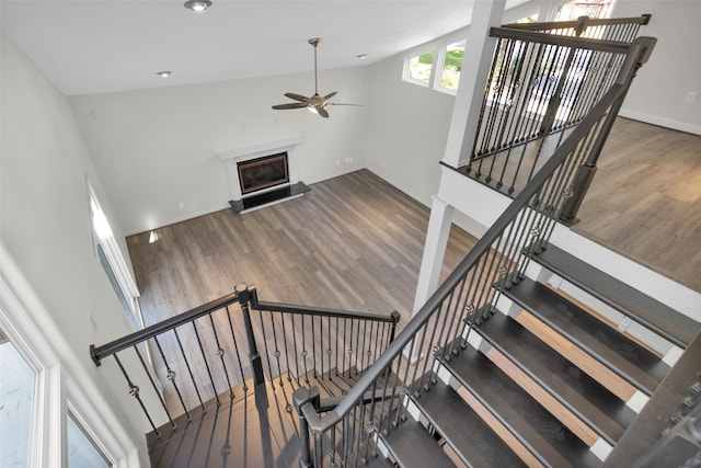 stairs with high vaulted ceiling, wood-type flooring, and ceiling fan