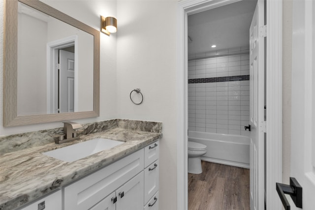 full bathroom with vanity, tiled shower / bath combo, toilet, and wood-type flooring