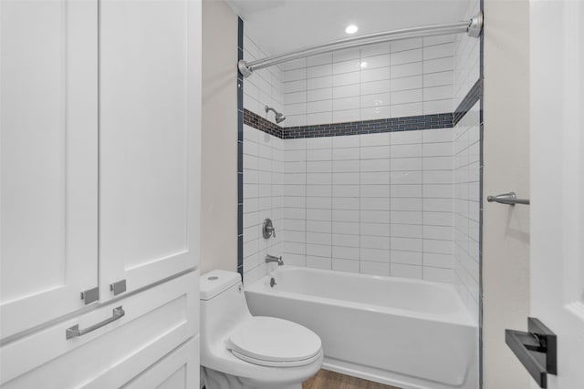 bathroom featuring hardwood / wood-style flooring, tiled shower / bath, and toilet