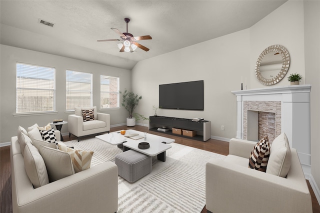 living room with hardwood / wood-style flooring, ceiling fan, a fireplace, and vaulted ceiling