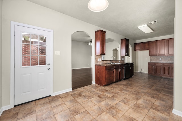 kitchen featuring decorative backsplash, ceiling fan, sink, dark stone countertops, and black dishwasher