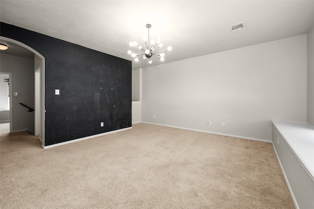 carpeted spare room with an inviting chandelier