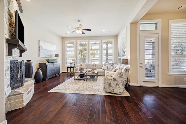 living room featuring ceiling fan, a fireplace, and dark wood-type flooring