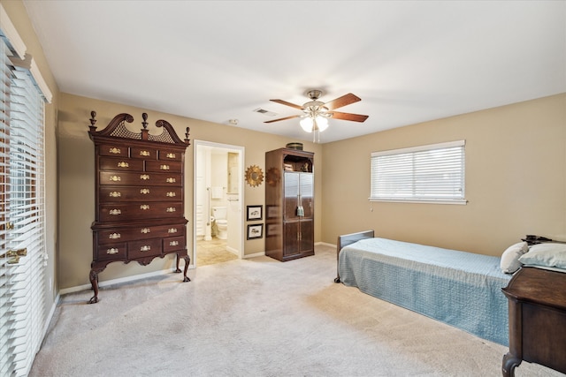 bedroom with ceiling fan, light carpet, and ensuite bath