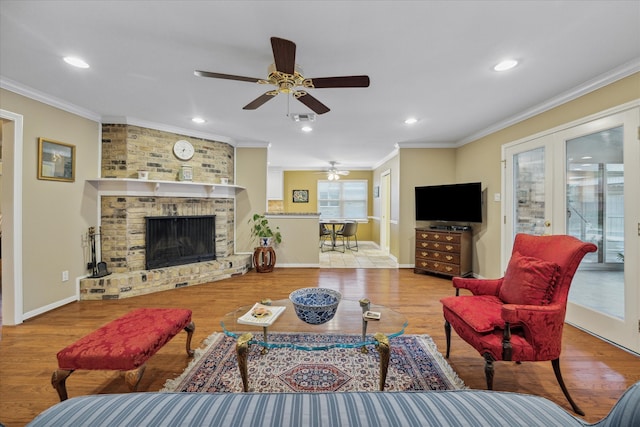 living room with ornamental molding, a fireplace, light wood-type flooring, and ceiling fan